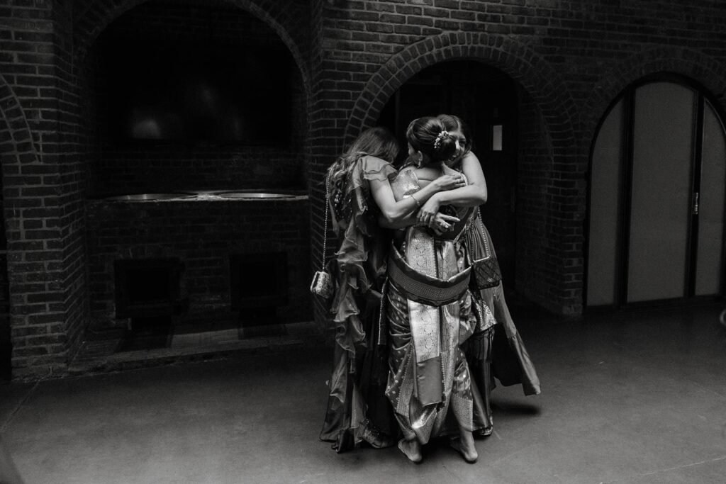 a group of women wearing dresses share a hug captured by a new york and traveling wedding photographer