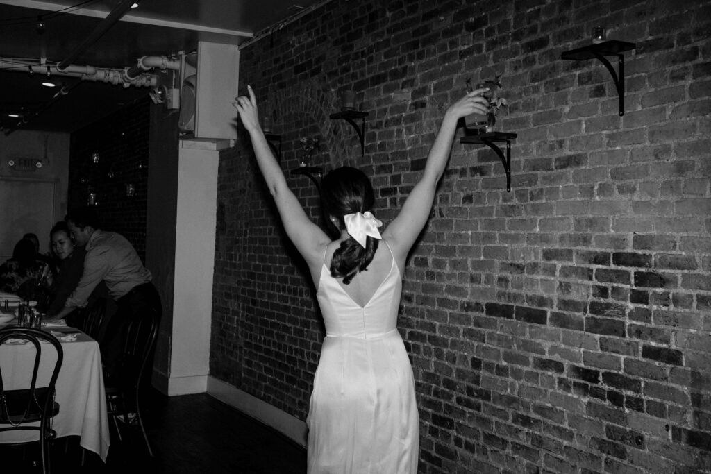 wedding photographer captures a candid of a bride with her arms in the hair during her wedding reception