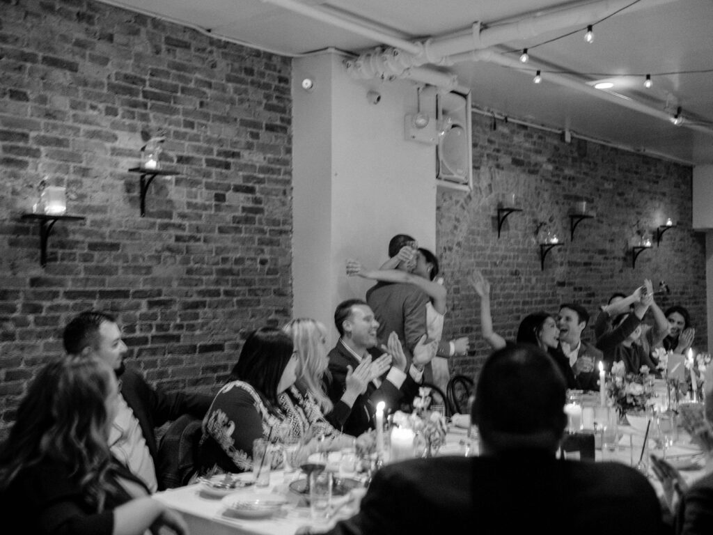 wedding photographer captured a pair of newlyweds kissing as all the guests around them celebrate