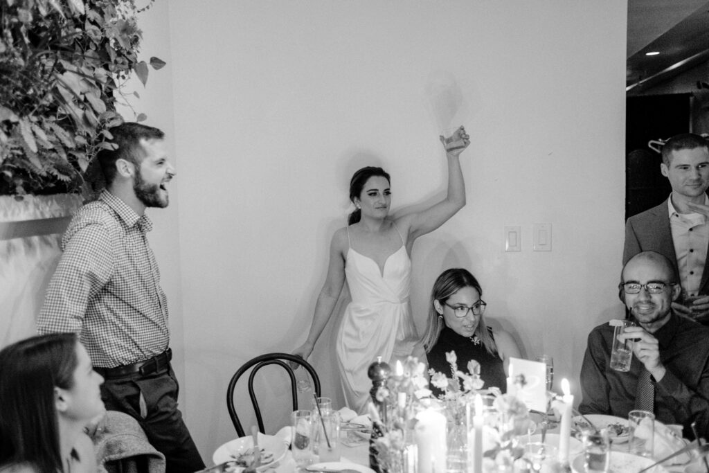 a wedding photographer captures a bride with a group of wedding guests with her glass raised