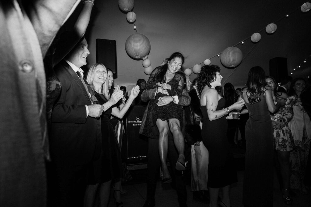 a group of wedding guests smile and laugh on the dance floor