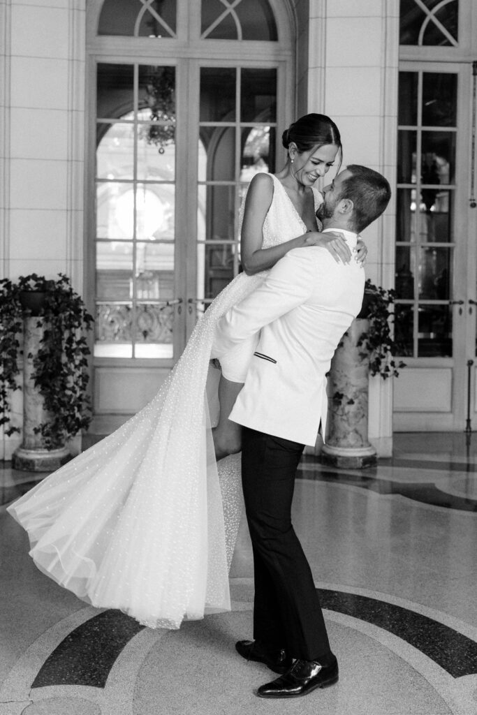 a pair of newlyweds gaze at each other during an embrace in front of their wedding photographer