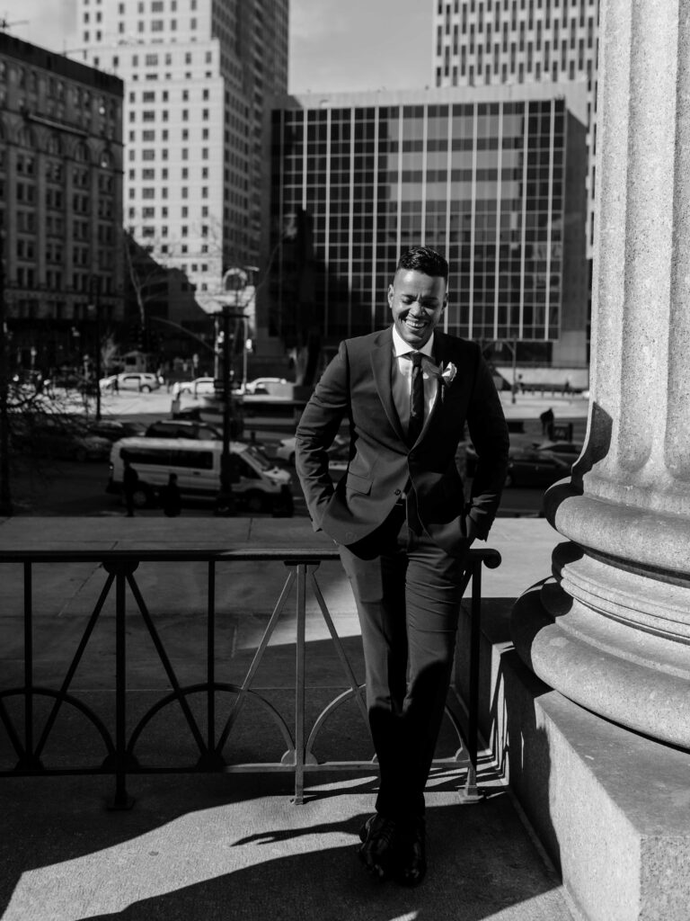 a groom laughs during photos with a wedding photographer