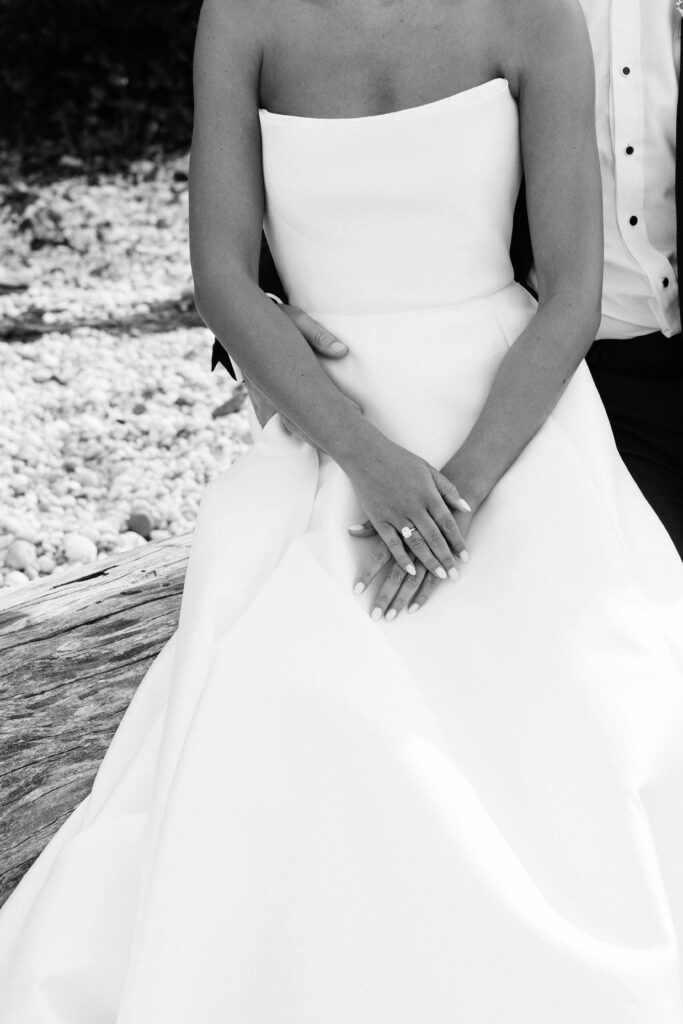 a pair of newlyweds sit together leaning against each other during photos with a wedding photographer