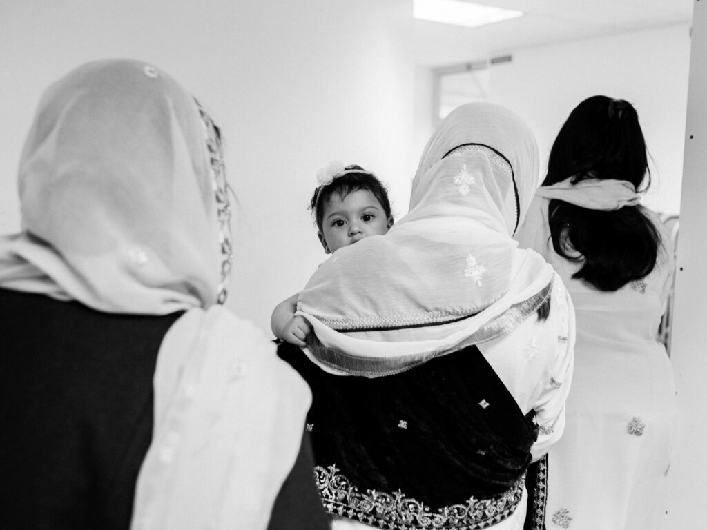 a baby peers over a woman's shoulder