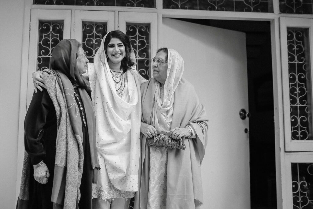 a woman stands smiling between two older women