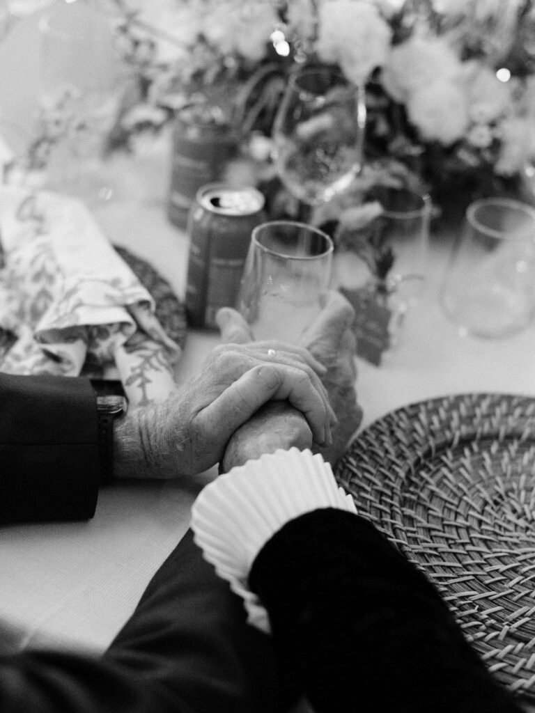 wedding photographer s photo of two elderly hands in an embrace at a wedding table