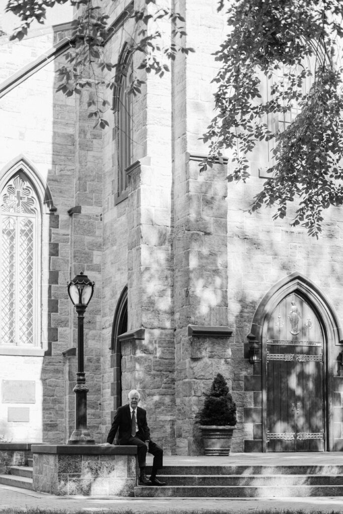 an older man sits in front of a brick church